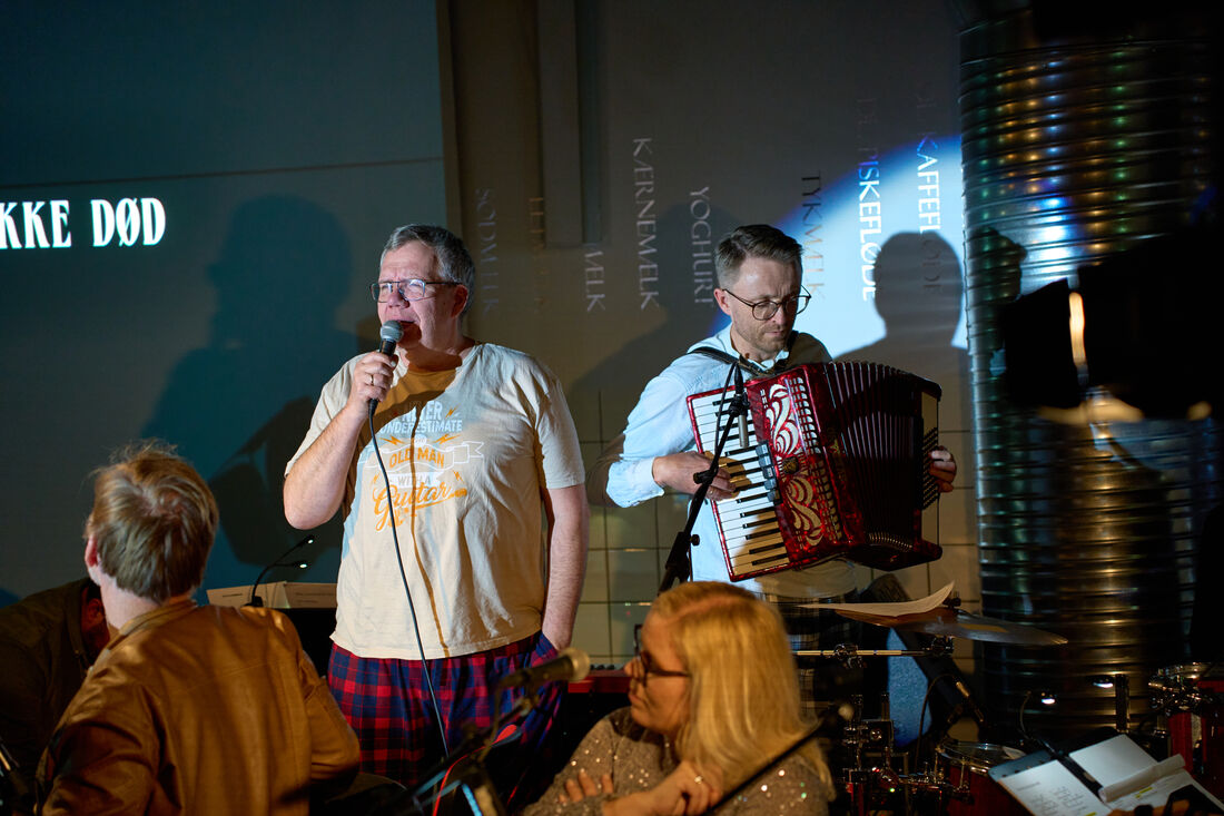 Sanger med mikrofon og harmonikaspiller på scenen