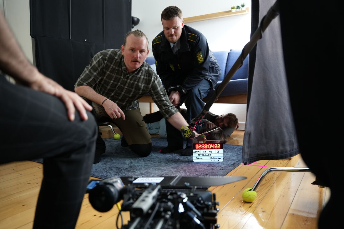 Instruktør og skuespiller i politiuniform på et filmsæt med klaptræ