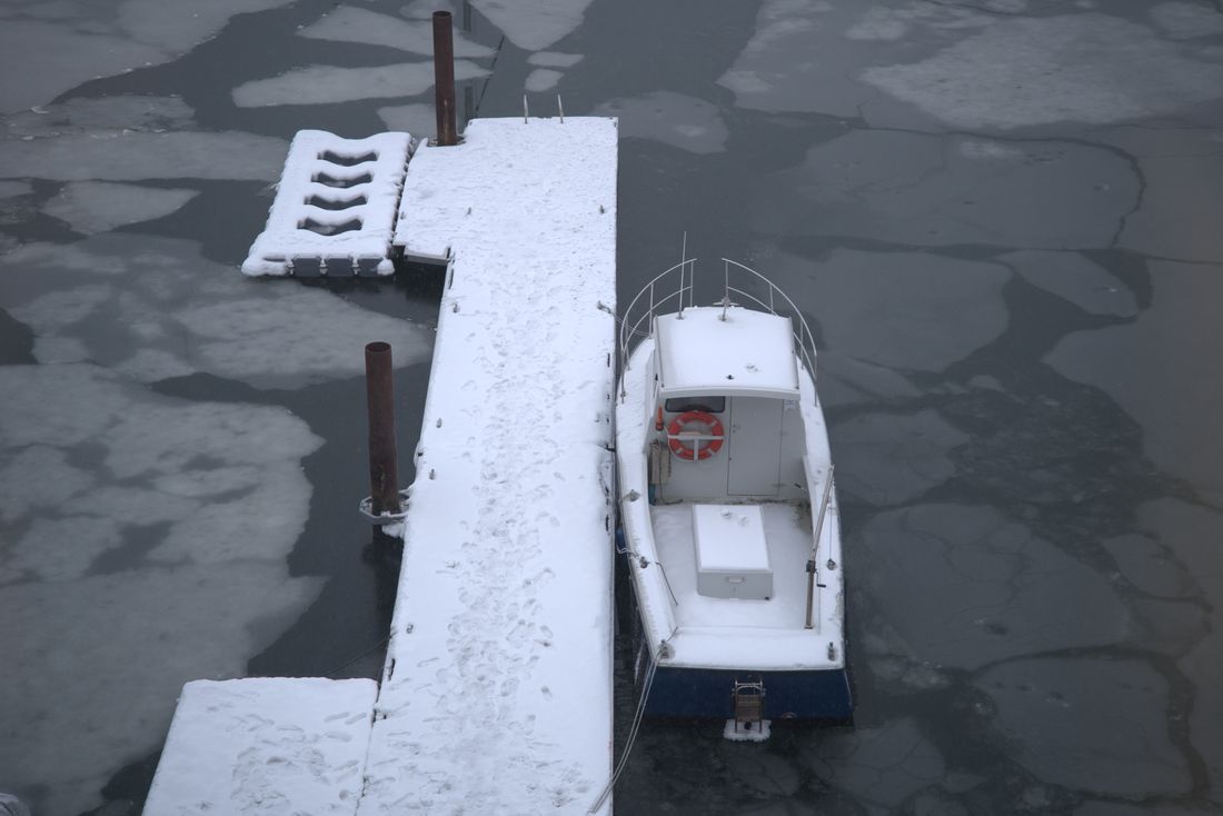 Snedækket båd ved en brygge i en frossen havn set oppefra
